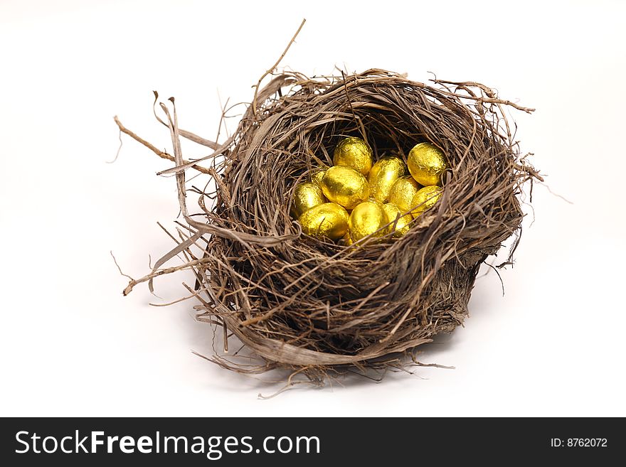 Golden chocolate eggs in the nest isolated on white background. Golden chocolate eggs in the nest isolated on white background