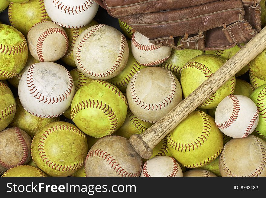 A picture of baseballs, softballs, a bat and glove. A picture of baseballs, softballs, a bat and glove