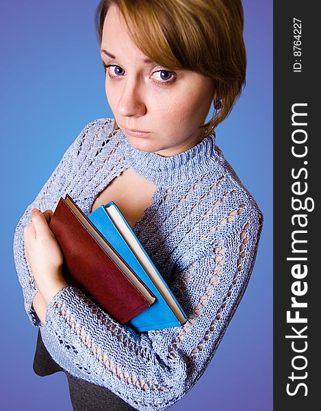 Young naive girl holding a books on blue background