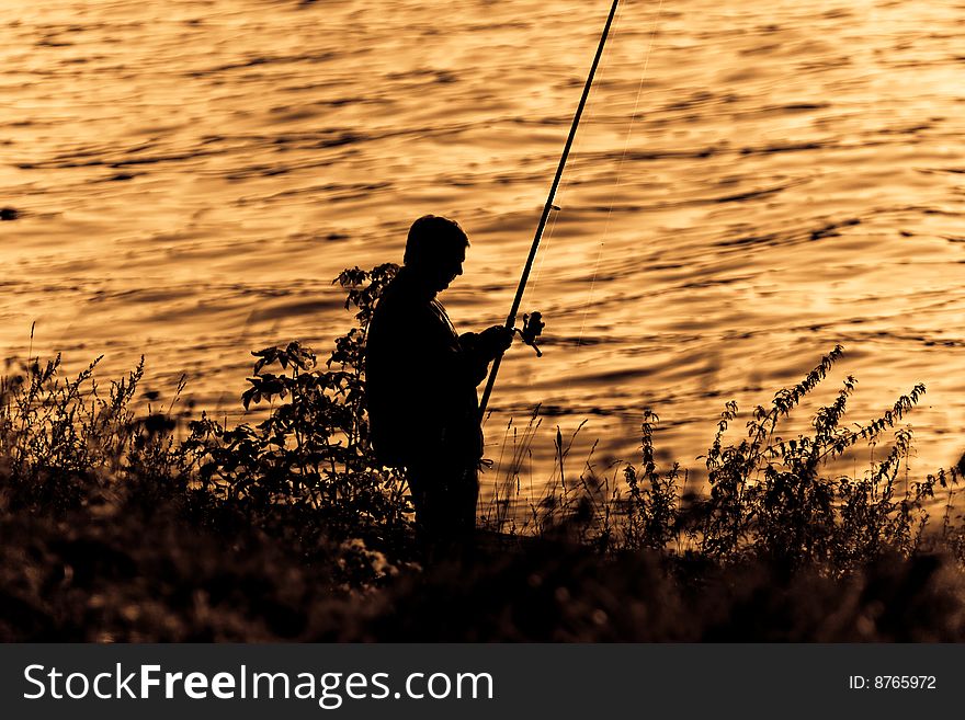 Fisherman Silhouette On Sunset.