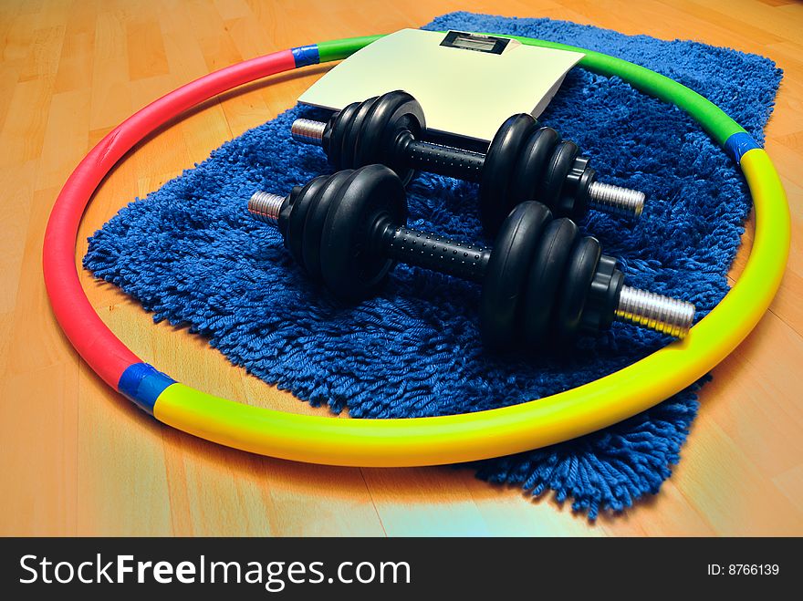 Dumbbells, hoop and scales on mat. Dumbbells, hoop and scales on mat.