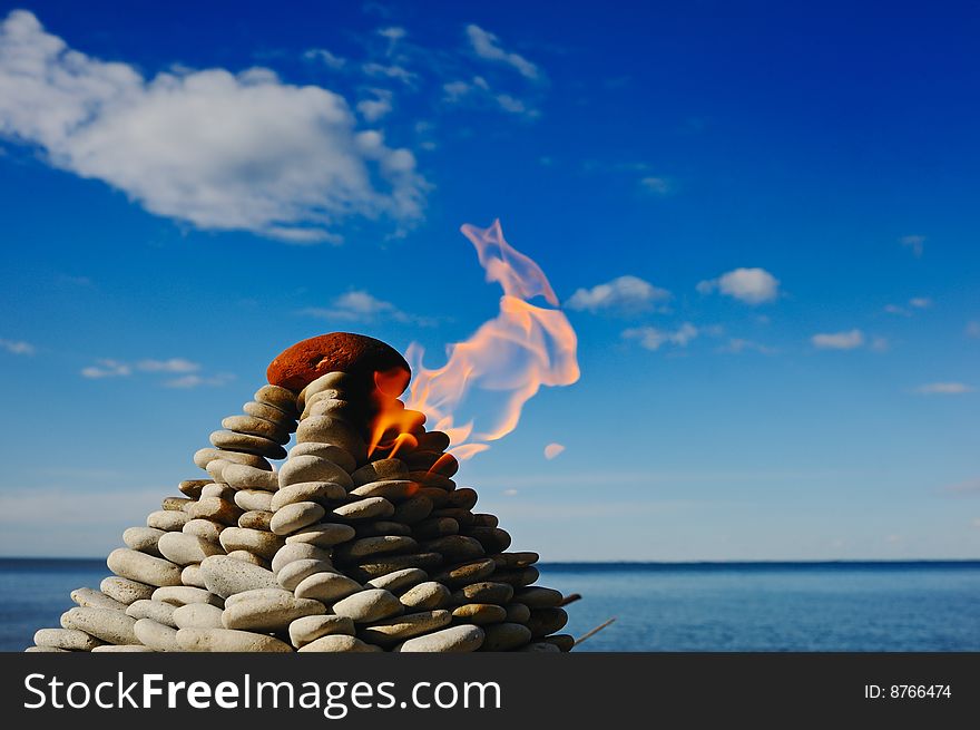 Torch at top of a pyramid from small stones. Torch at top of a pyramid from small stones