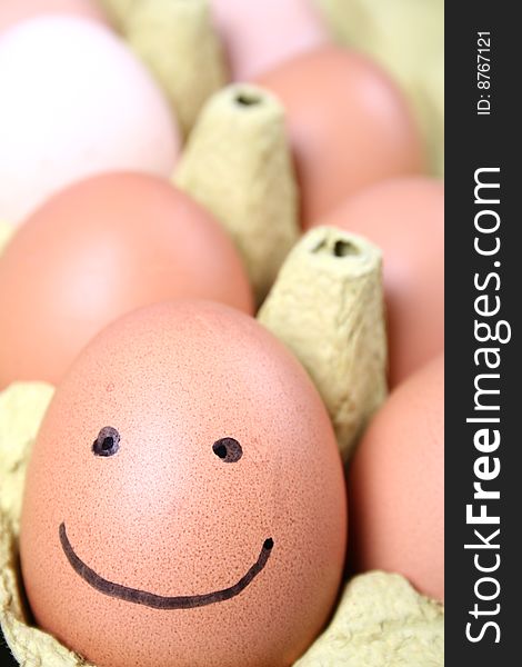 Eggs in a carton one with a smiling face