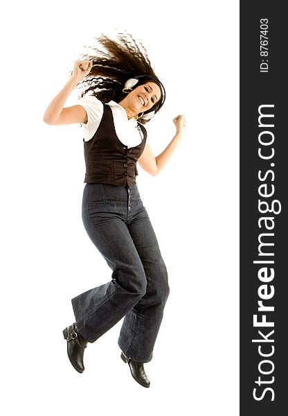 Beautiful female enjoying music and jumping against white background