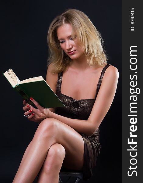 Beautiful girl reads the book against a dark background