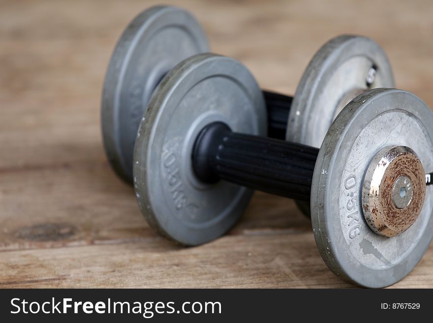 Two dumbbells lying on the wooden ground