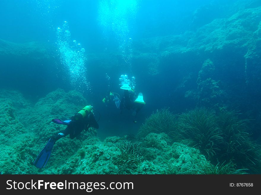 Divers in the mediterranean sea on a cave`s entrance. Divers in the mediterranean sea on a cave`s entrance.