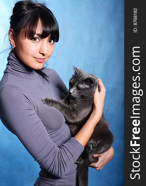 Beautiful woman in gray holding gray cat inger hands. Beautiful woman in gray holding gray cat inger hands