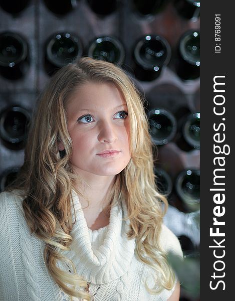 Blond teen girl next to wine rack. Blond teen girl next to wine rack