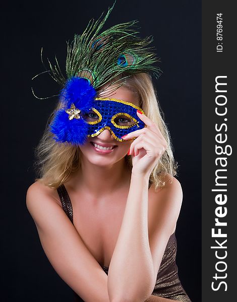 Beautiful girl in carnival mask against a dark background