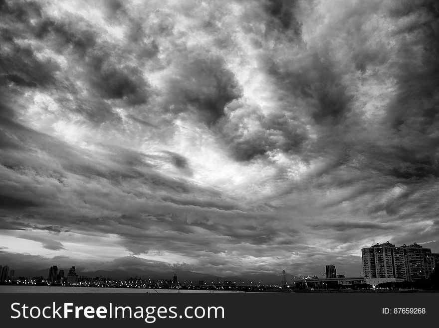 A black and white view of cloudy skies above a city. A black and white view of cloudy skies above a city.
