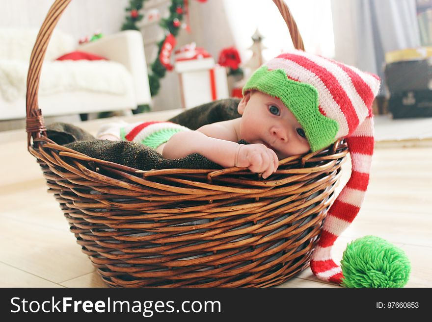 Cute baby in Christmas hat playing in wicker basket. Cute baby in Christmas hat playing in wicker basket.