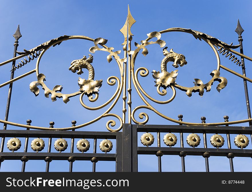 Gold plated gates decoration against the blue sky background. Gold plated gates decoration against the blue sky background