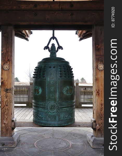 A bell carved with Japanese words Bell of Happiness. The door shaped hanging frame is a metaphor of door to happiness