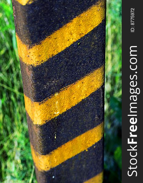 Green grass and old pole with grungy yellow stripes