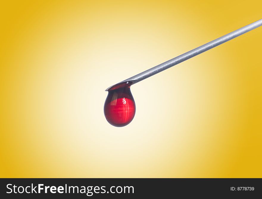 Syringe needle with a drop of blood.