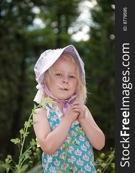 A young blonde girl in old fashioned summer clothes outside in the garden. A young blonde girl in old fashioned summer clothes outside in the garden.