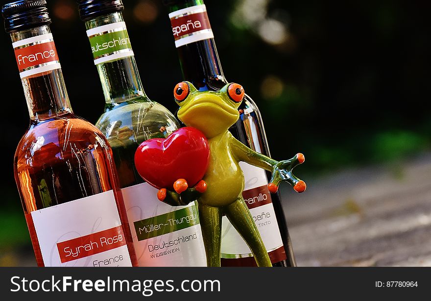 Green Frog With Red Heart Figurine Beside Glass Bottles