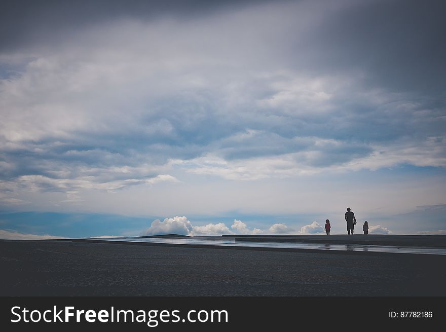Silhouettes of father and children on an empty beach. Silhouettes of father and children on an empty beach.