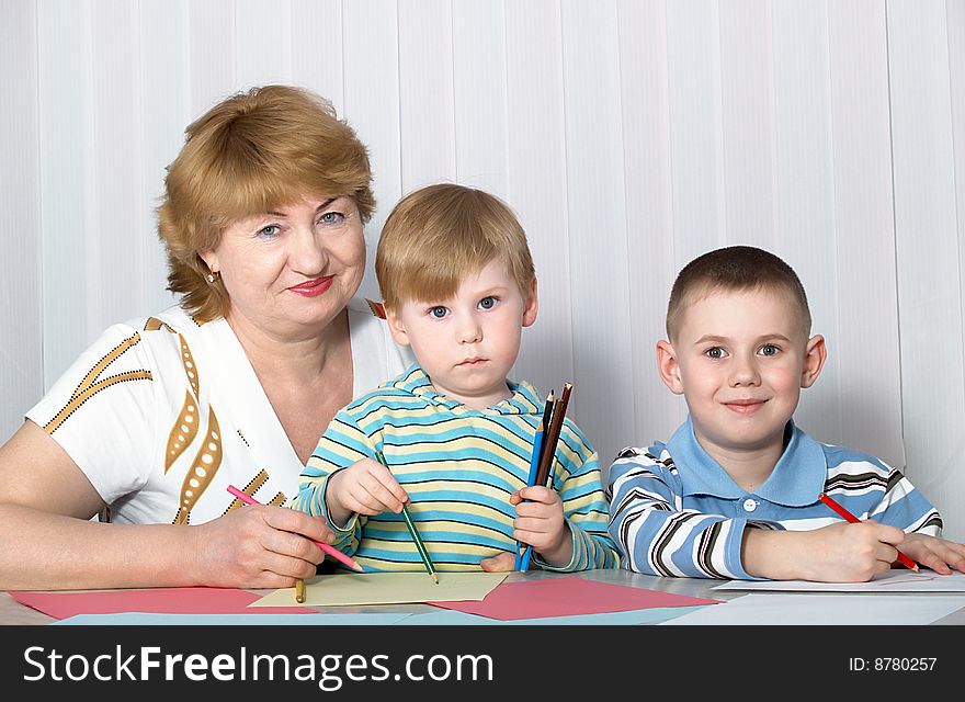 The grandmother with two grandsons is engaged behind a table. The grandmother with two grandsons is engaged behind a table