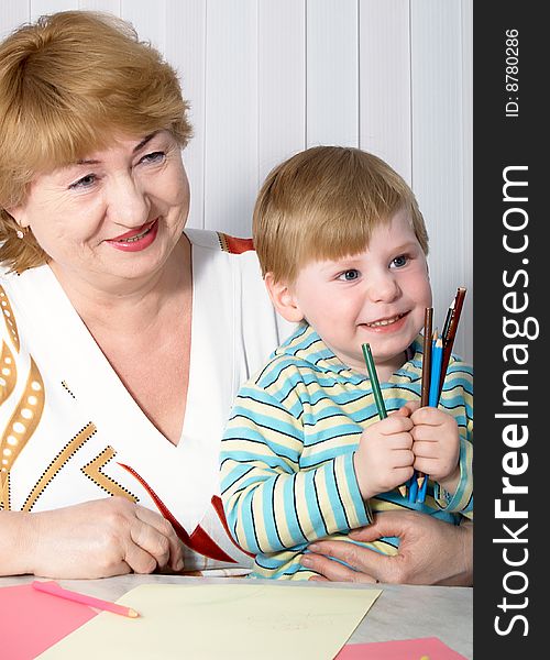 The grandmother with grandson is engaged behind a table. The grandmother with grandson is engaged behind a table