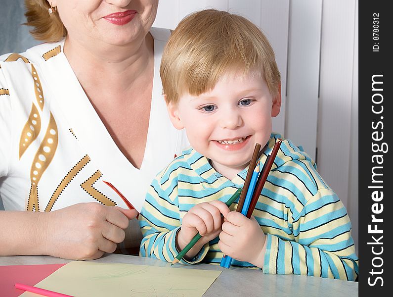 The grandmother with grandson is engaged behind a table. The grandmother with grandson is engaged behind a table