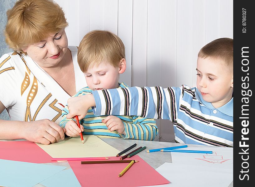 The grandmother with two grandsons is engaged behind a table. The grandmother with two grandsons is engaged behind a table