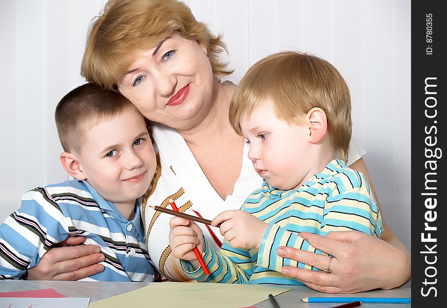 The grandmother with two grandsons is engaged behind a table. The grandmother with two grandsons is engaged behind a table