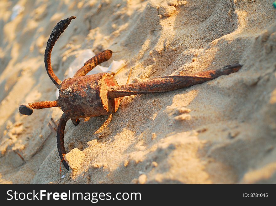 Rusty old anchor lying in the sand on the beach