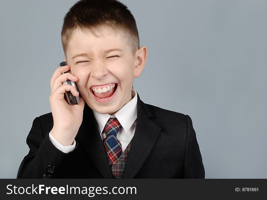 Laughing boy in a jacket with mobile phone