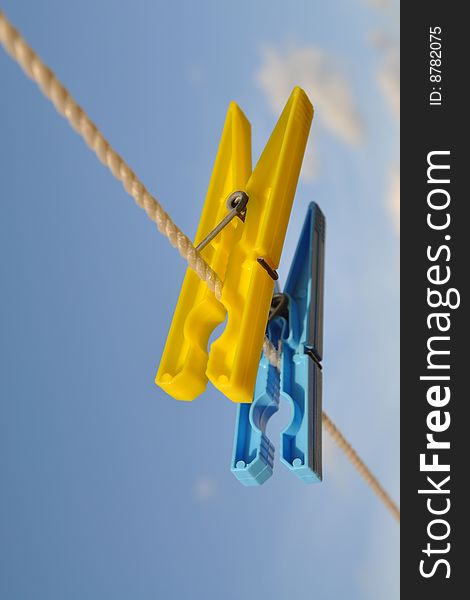 A pair of blue & yellow laundry clips against blue sky. A pair of blue & yellow laundry clips against blue sky.