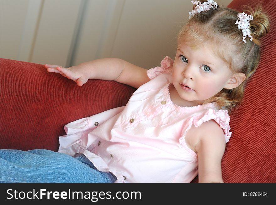 A little girl sitting on a red couch