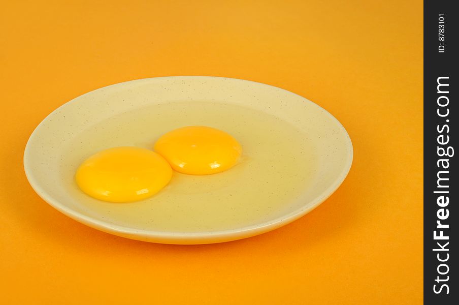 Two egg yolk in the dish, yellow background. Two egg yolk in the dish, yellow background