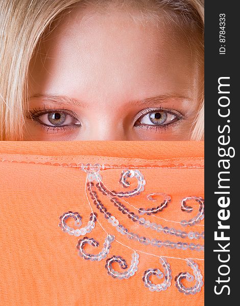 Beautiful woman's face closed by an orange scarf. Beautiful woman's face closed by an orange scarf