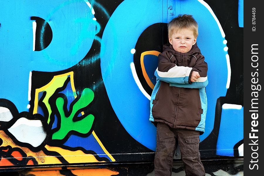 Young boy looking tough against graffiti wall. Young boy looking tough against graffiti wall.
