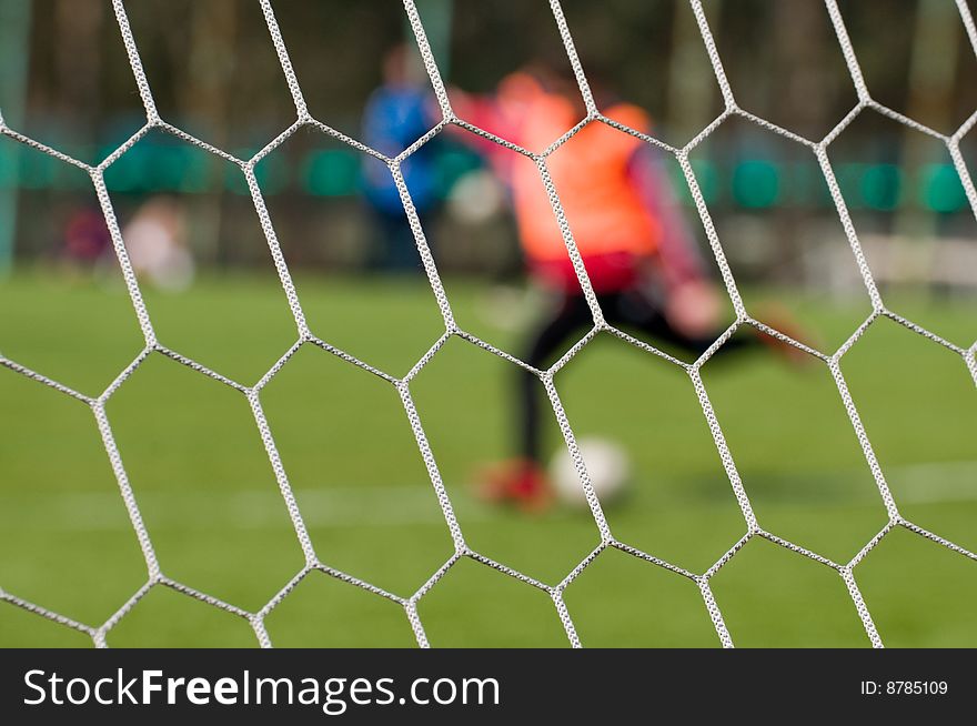 Football ground and football players through a grid of gate - an abstract dim background. Football ground and football players through a grid of gate - an abstract dim background.