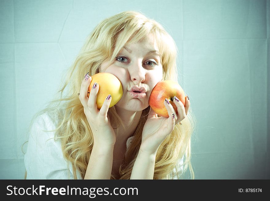 Portrait of a young blonde girl with apples in the white background