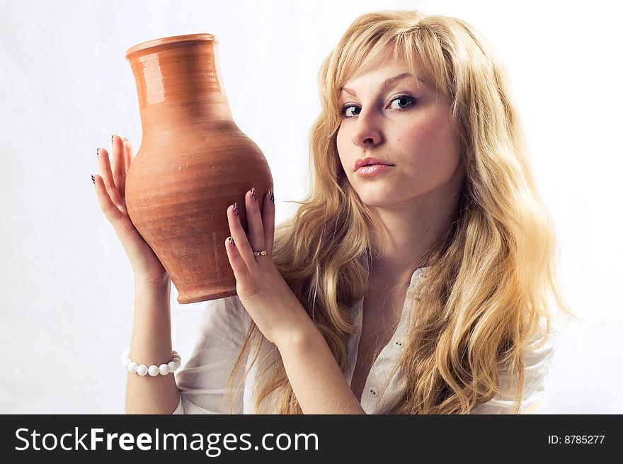 Portrait of a young blonde girl with jug in the white background