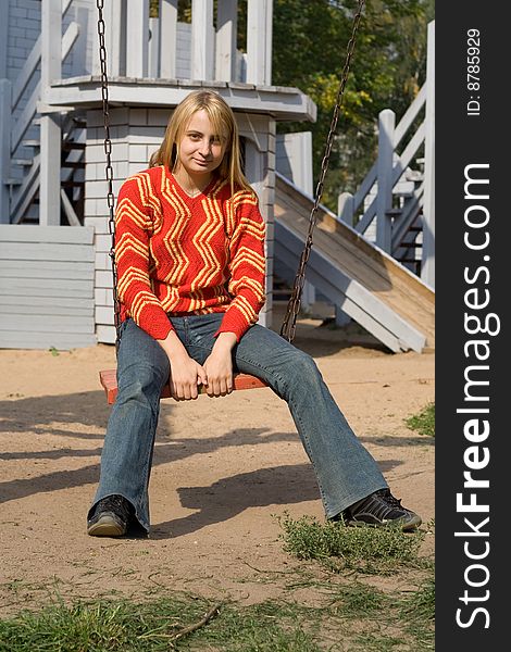 Girl in red pullover sitting on swing