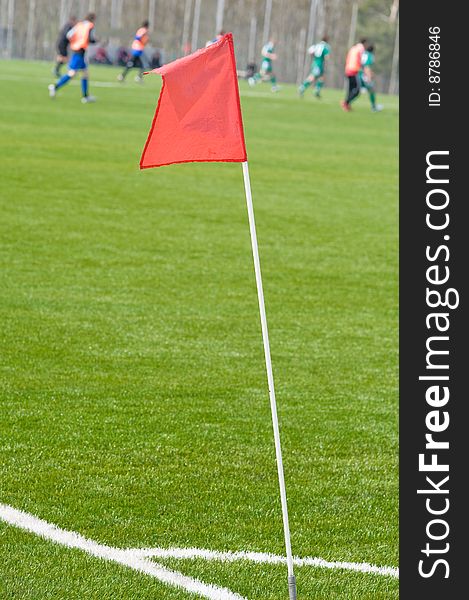 Red tag at the corner of a football ground and on a background players. Red tag at the corner of a football ground and on a background players.