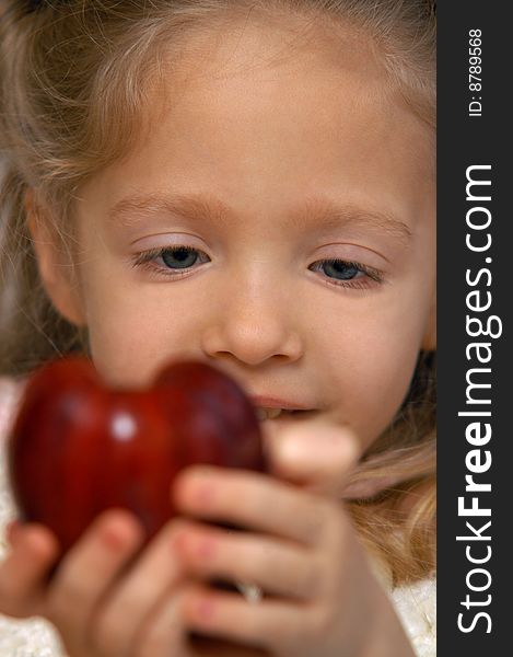 A young girl holds an apple in her hand. A young girl holds an apple in her hand.