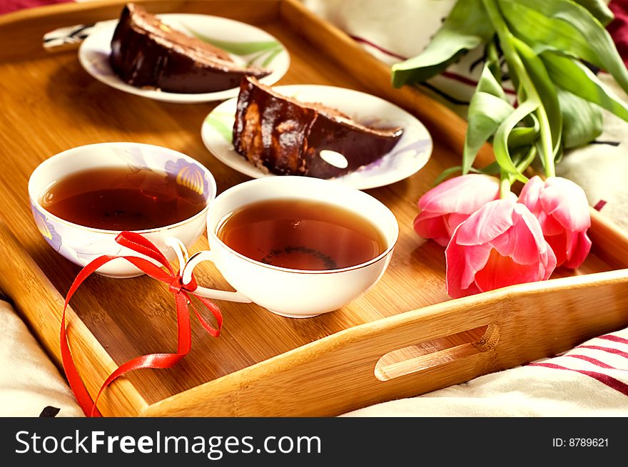 Breakfast tray on bed with tea, cakes and tulips. Breakfast tray on bed with tea, cakes and tulips