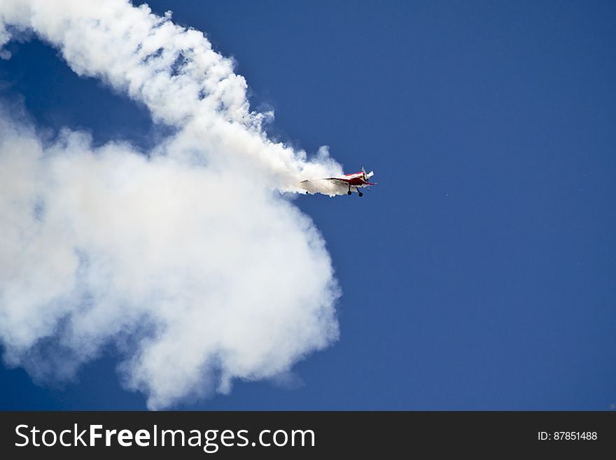 A low wing Sukhoi Su-31 monoplane covered in smoke after performing a loop. A low wing Sukhoi Su-31 monoplane covered in smoke after performing a loop.