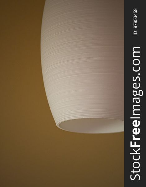 White ceramic ceiling lamp against mustard colored wall.