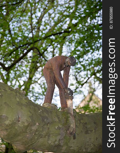 A mettalic work of art representing a woodcutter using a saw on a branch of a tree. A mettalic work of art representing a woodcutter using a saw on a branch of a tree.