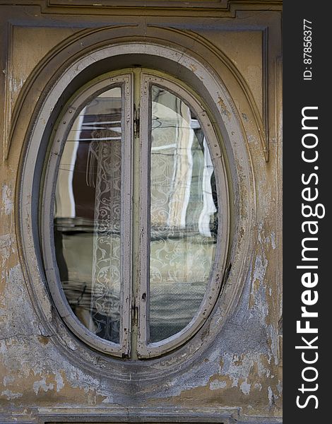 Photo Of An Oval Shaped Window Frame On Old House Facade.