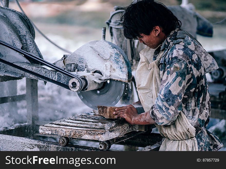A carpenter in military uniform cutting wood using a circular saw. A carpenter in military uniform cutting wood using a circular saw.