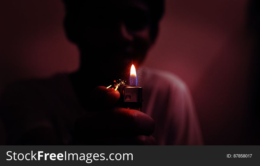 Boy (person) in dark room carrying a lighted candle to see their way. Boy (person) in dark room carrying a lighted candle to see their way.
