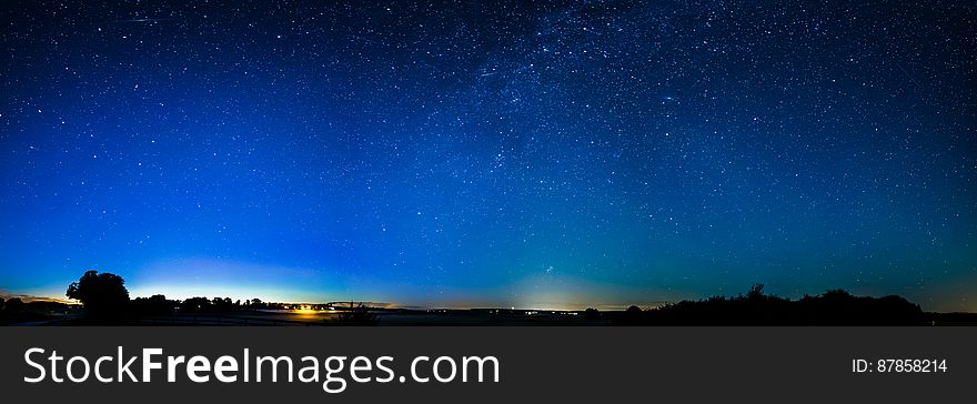Starry night sky with silhouetted landscape.