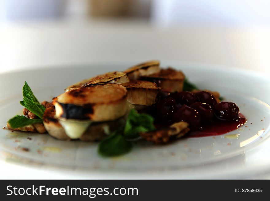 A plate of fried cheese with cherries and mint.